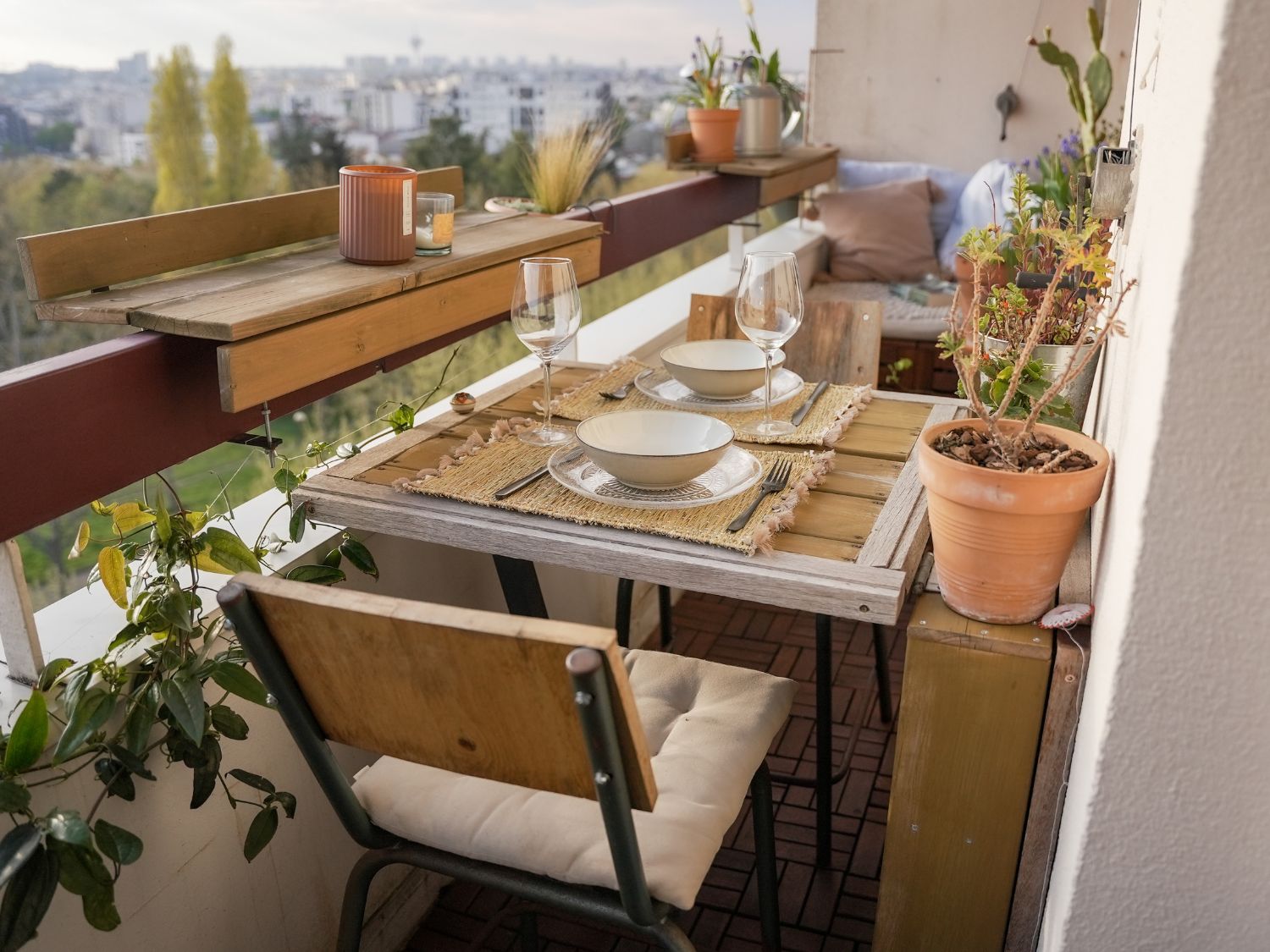 Réalisation d'aménagement de petit balcon en longueur par Petites Garrigues à Montreuil, avec une table en bois sur mesure, des chaises et des coffres de rangement en arrière plan