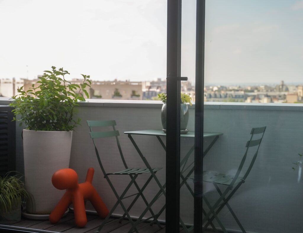 aménagement d'un petit balcon en longueur à Paris, avec des pots en terre cuite et une petite table verte